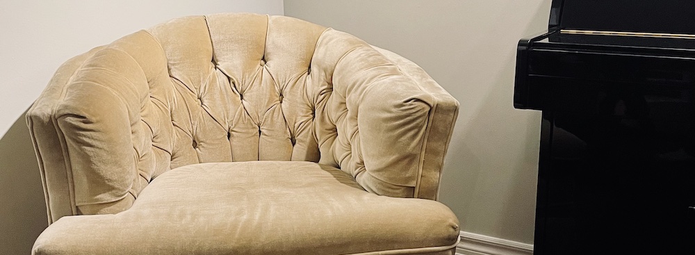 vintage velvet arm chair next to a black piano