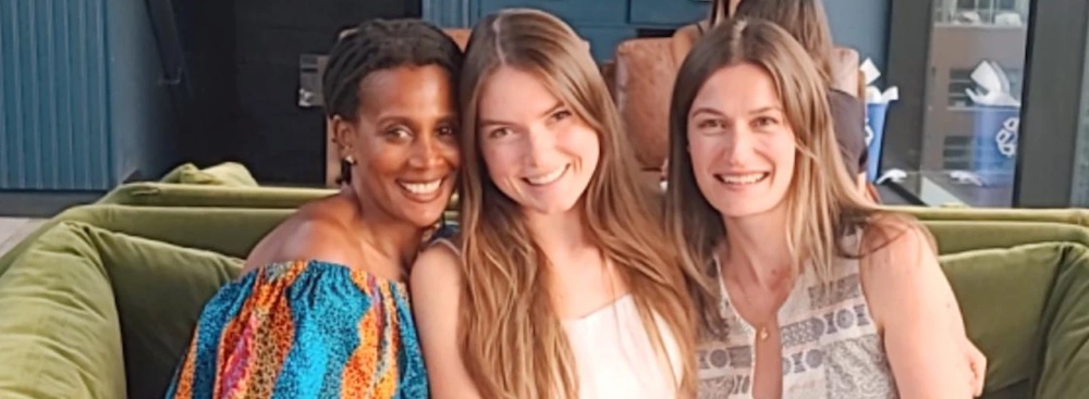 Three women on a couch enjoying a drink