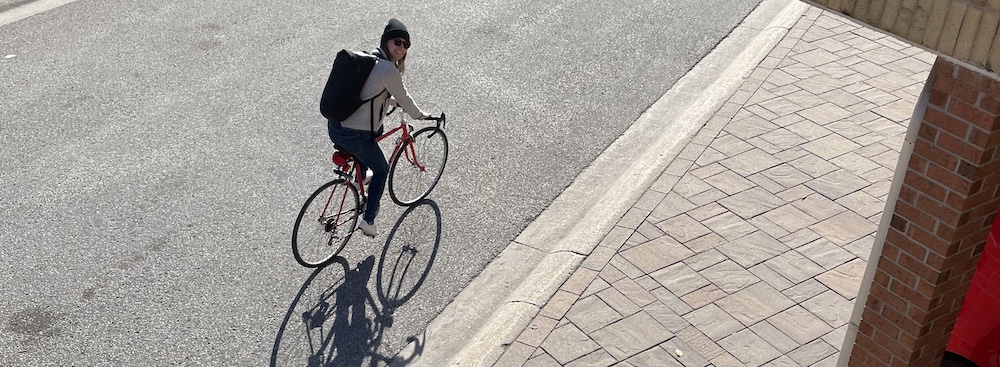 a woman riding a bike, turning toward the camera and smiling.