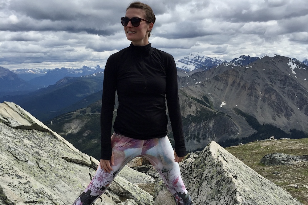 a girl standing at the summit of a peak and on top of a rock