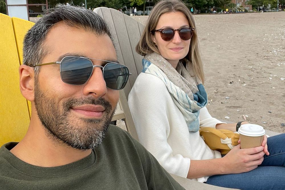 man and woman sitting on chairs on a beach at the waters edge