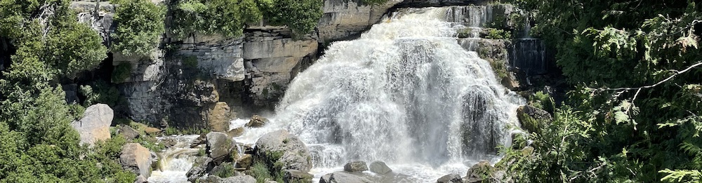 a waterfall surrounded by large rocks and green trees